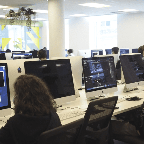 Workroom with students working on iMacs in the campus of 42 Québec (Canada)